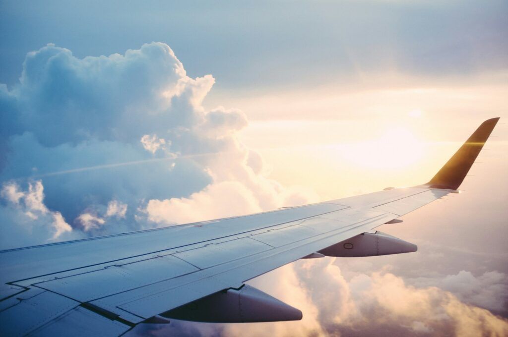 Airplane wing above the clouds at sunset