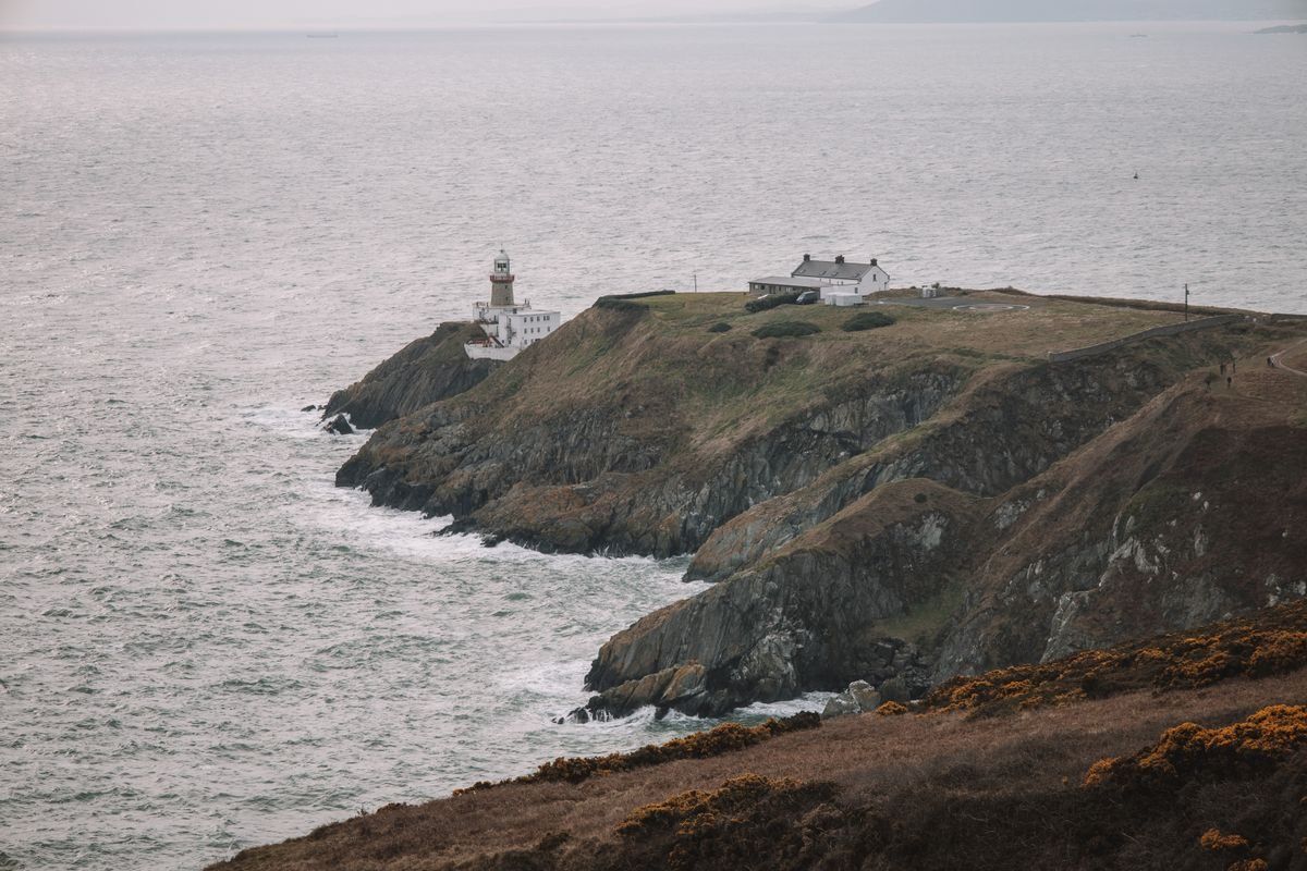Baily Lighthouse on a rocky headland above the sea at Howth Head