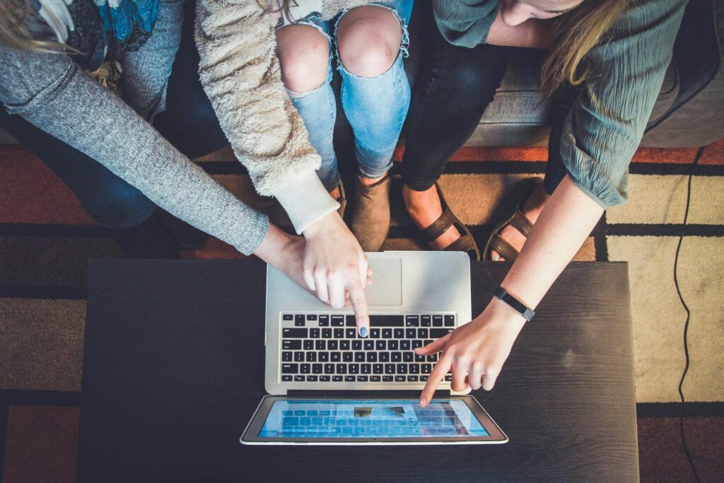Friends pointing at a laptop screen while choosing a trip