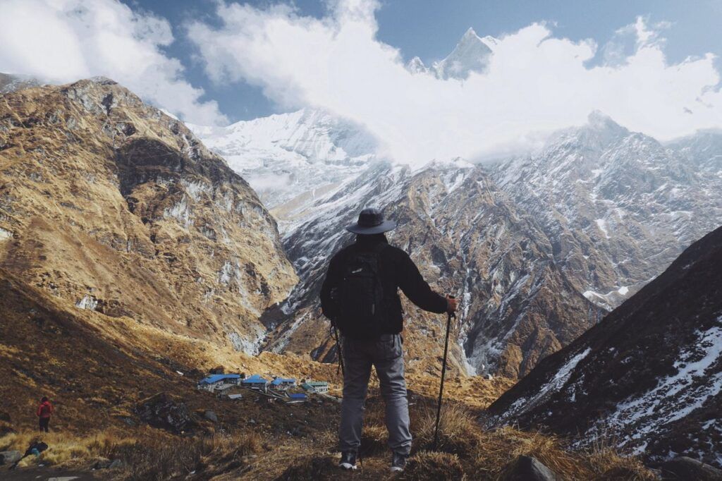 Hiker with trekking poles looking at the high Himalayas in Nepal