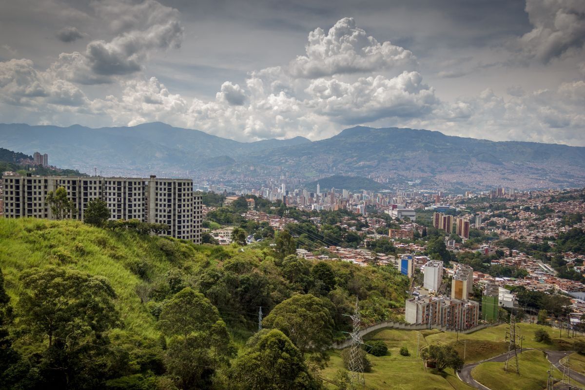 Medellín urban valley surrounded by green hills and mountains beneath large clouds