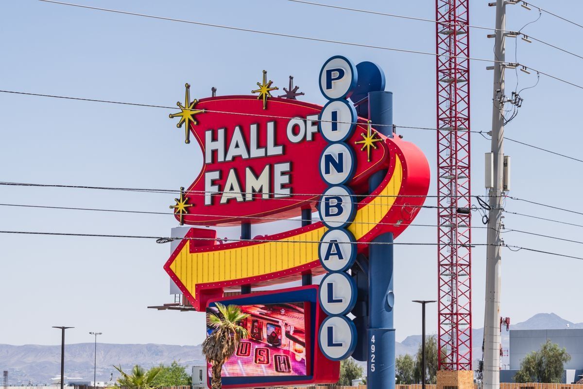 Pinball Hall of Fame sign with red arrow and blue lettering against a clear daytime sky