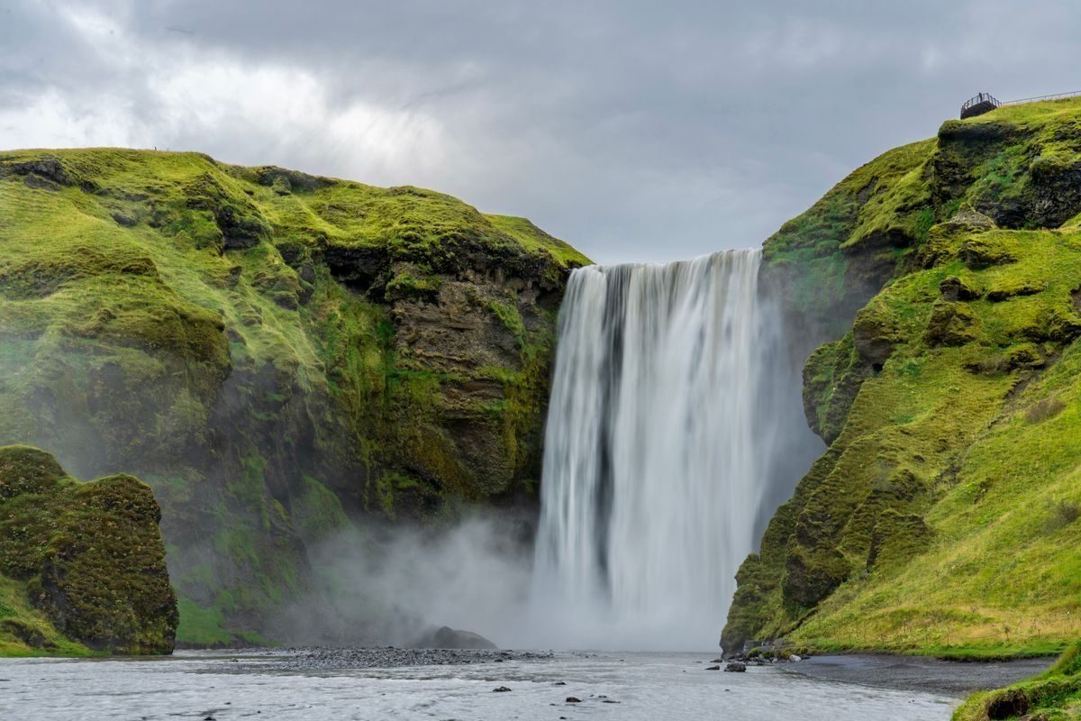 Skógafoss waterfall pouring between mossy green cliffs in Iceland