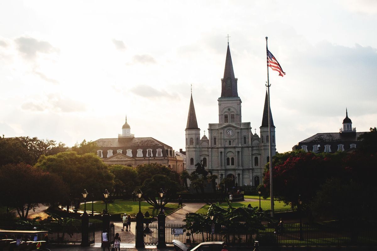 St. Louis Cathedral behind a garden and American flag at sunset