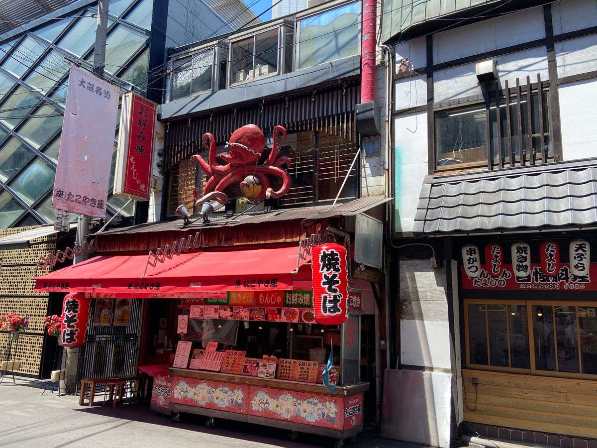 Street food shop with a large octopus sculpture above a red awning
