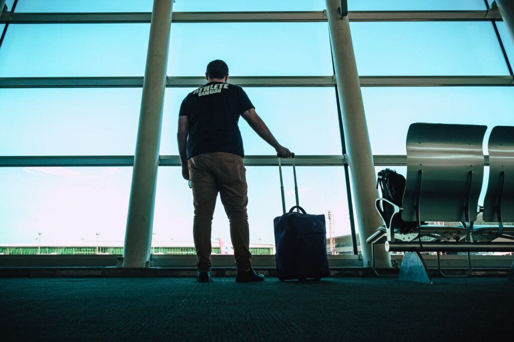 Traveler with a carry-on suitcase waiting at the airport gate before a flight