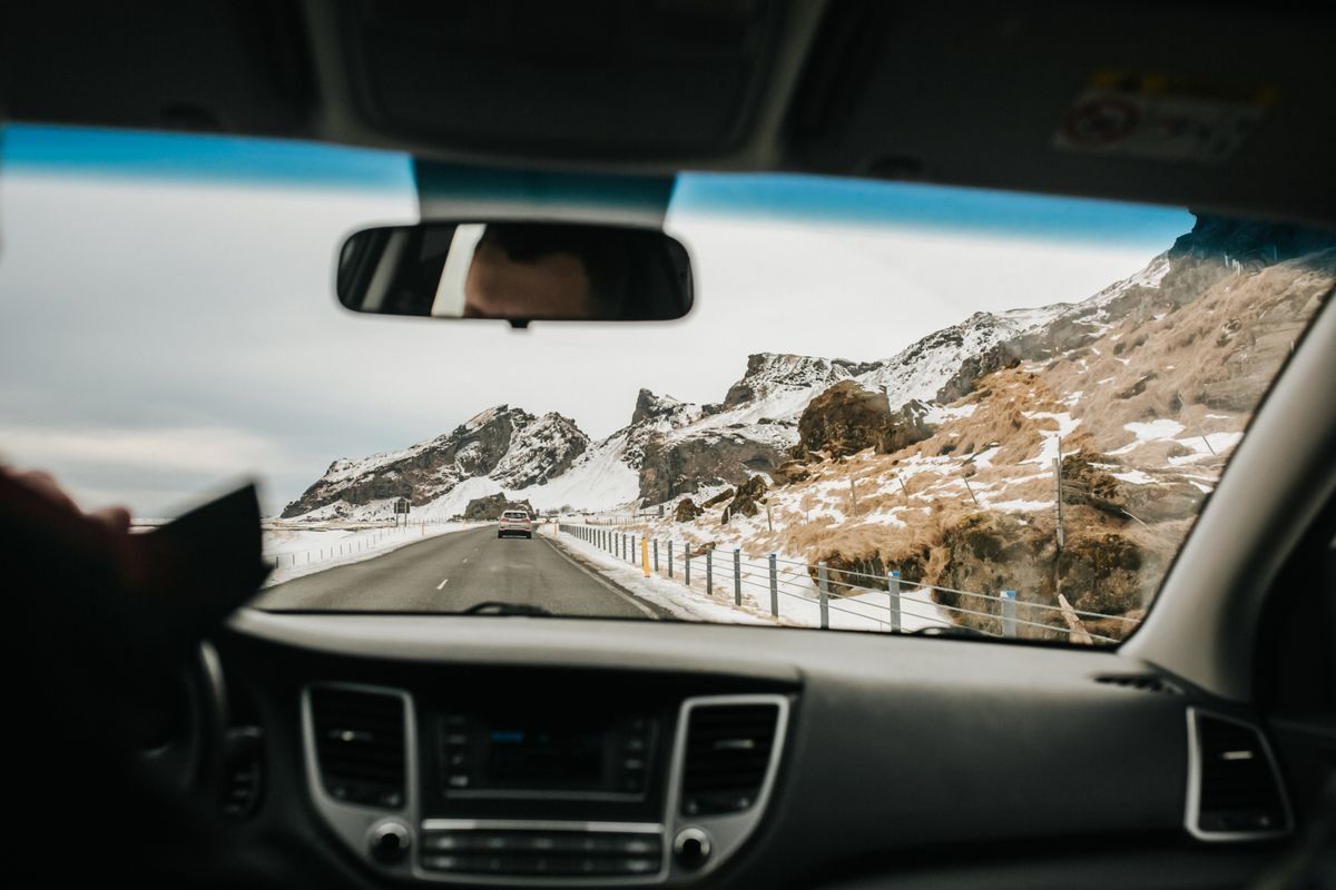 View from inside a car on a mountain road with snow-covered slopes