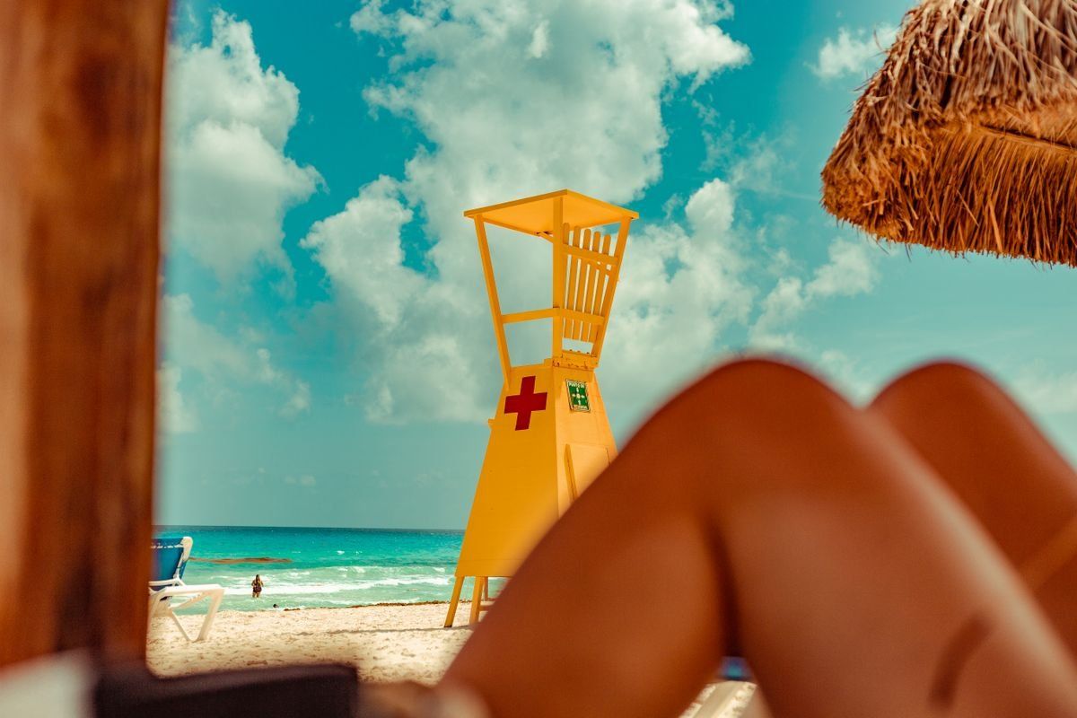 Yellow lifeguard tower on a sandy Cancun beach with turquoise sea and cloudy sky