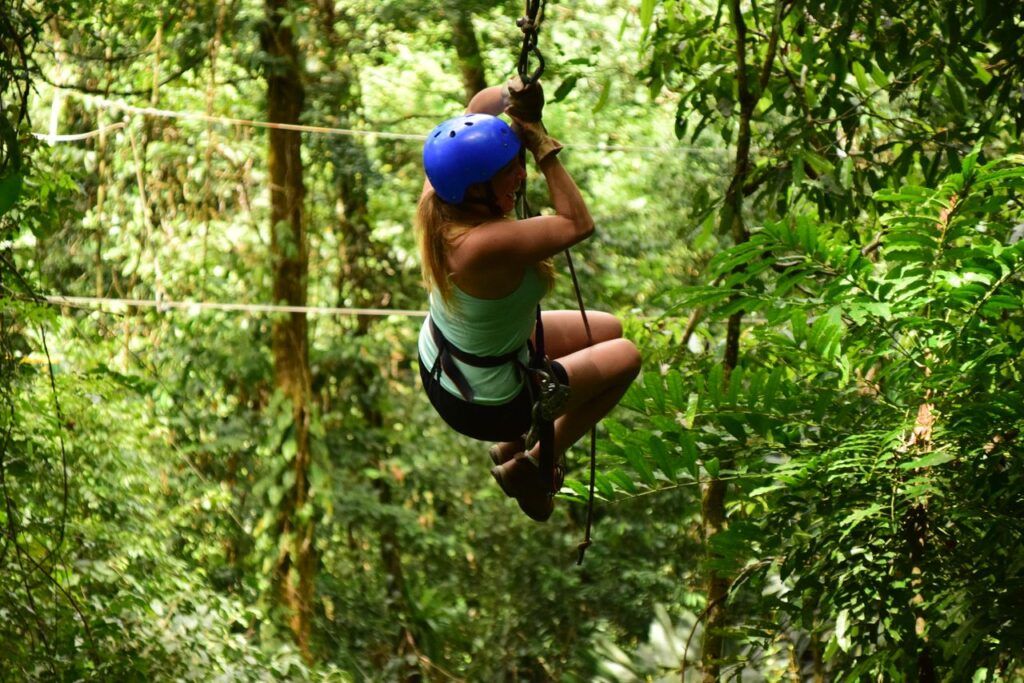 Traveler wearing a helmet zip-lining through the rainforest canopy in Costa Rica